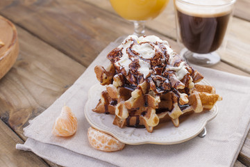 Sweet Belgian waffles for breakfast, decorated with white cream and chocolate sauce. Glass with coffee black and orange juice,fruit bananas and grapfruit. Free space for text or advertising