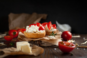 Toast with feta cheese on baking paper, cherry tomatoes and butter on a dark wooden table