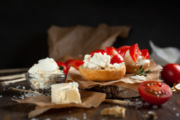 Toast with feta cheese on baking paper, cherry tomatoes and butter on a dark wooden table