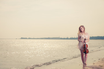 Woman on beach near sea holding violin