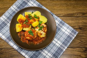 Baked meatballs in tomato sauce on a wooden background