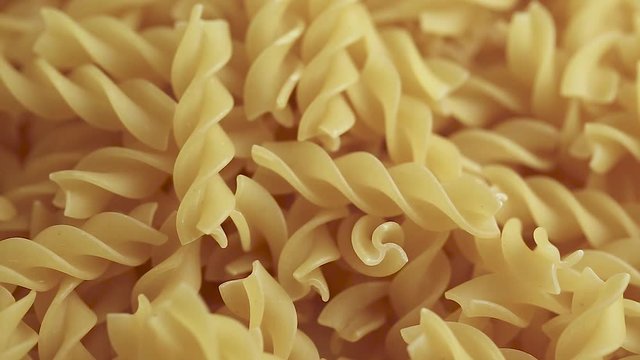 Twisted pasta from durum wheat are scattered as a background