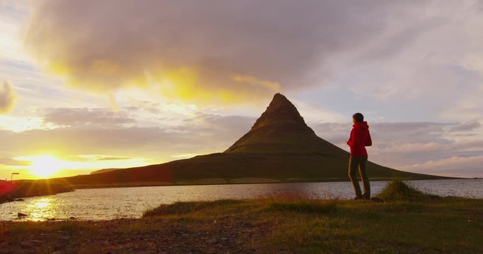 Sunset in Nature on Iceland. Healthy active outdoor lifestyle video of woman watching sunset in nature on Iceland. Kirkjufell mountain landscape on West Iceland. Iceland tourist destination and icon.