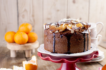 Homemade cake with tangerines and almonds, with chocolate. On a white plate, for breakfast. cups for tea. wooden background, space for writing text or advertising