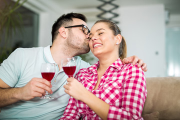 Photo of a young cheerful couple toasting at home with wine.