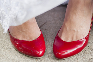 a woman wears red shoes during a wedding