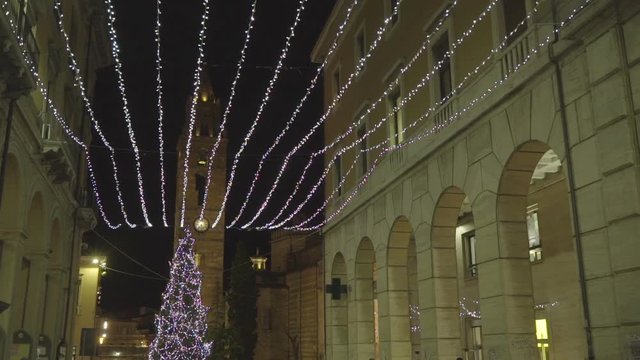 Some Christmas lights hanging above the street of the town centre at night.