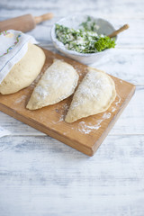Preparation of homemade pies with fresh herbs and cheese. Dough. A rolling pin and a towel with a pattern. Free space for text or advertising
