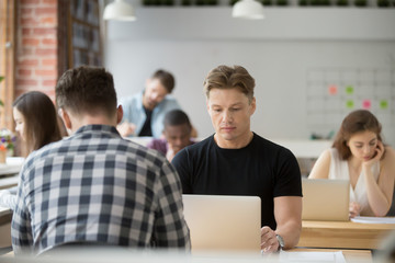 Serious businessman focused on laptop, man using pc sitting at shared office desk, busy developer programmer concentrated on work in co-working space, trader looking at screen monitoring stock online