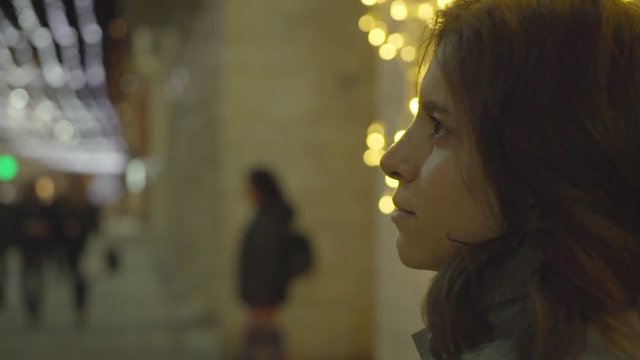 Girl filmed from the back, slowly turning her face left, looking at something and then softly smiling.