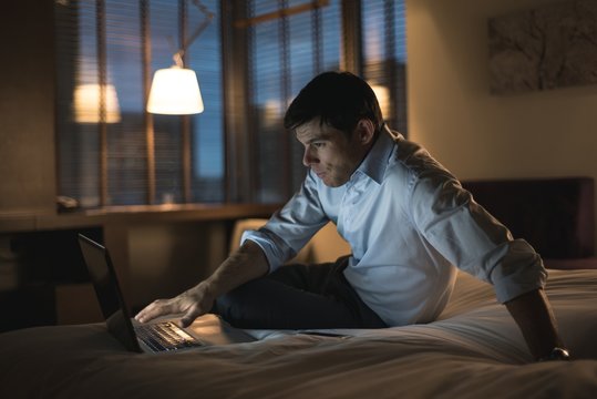 Businessman using laptop in bedroom