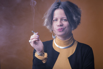 Fototapeta premium Portrait of a young woman smoking a cigarette on a yellow background