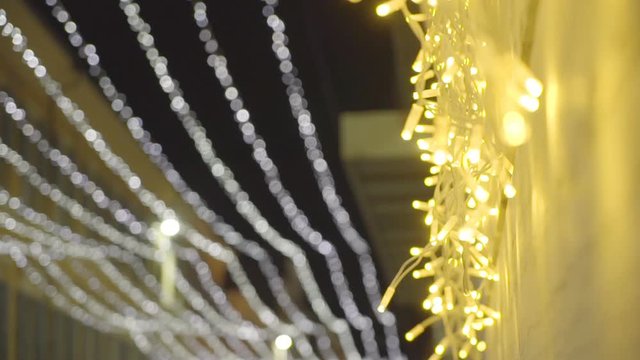 Christmas lights, yellow-colored, swinging in the air because of the wind.