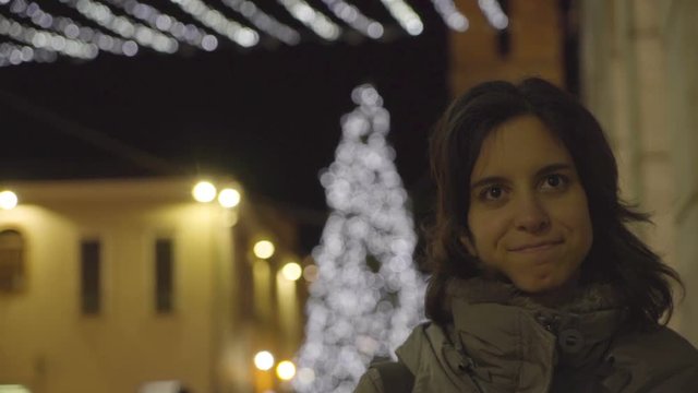 Girl smiling and swinging back and forth, Christmas tree in background, out of focus.
