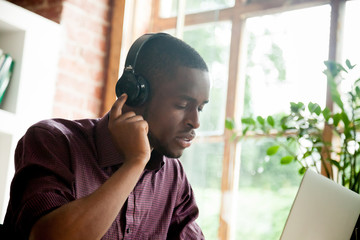 African american man enjoying good music in headphones with eyes closed, young black casual guy listening to favorite mp3 digital music on laptop wearing headset, relaxing with track for meditation