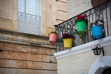 Fototapeta na wymiar Horizontal View Of a Balcony With Three Colored And Flowered Jars Hanged On It