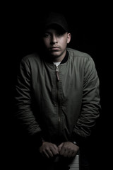 dramatic portrait of teen boy who brace to keyboard instrument in front of black background