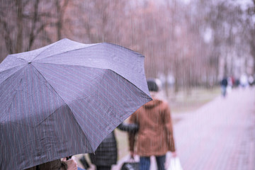 Close-up of dark umbrella during rain.