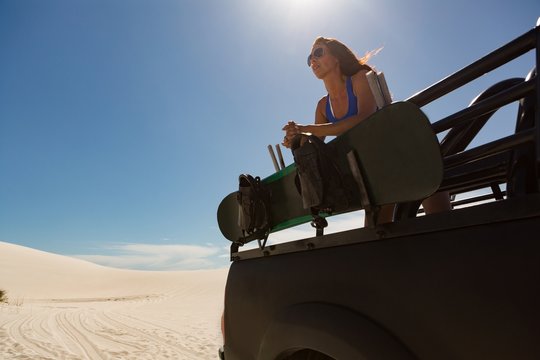 Woman standing in open jeep on sand dune