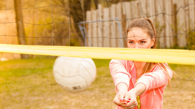 Sports games and people concept. Young woman in sportswear volleyball player in action outdoor on court