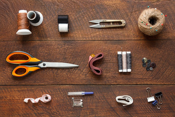 Flat lay aerial image of fashion designer items background concept.Top view sewing accessory or tailor equipment on modern rustic brown wooden at home office desk studio.Crafting tools in work shop.