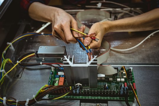 Female worker attaching a wire on circuit board