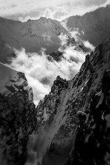 Skały, wysokie góry, ośnieżone szczyty w chmurach. © elisabeth3