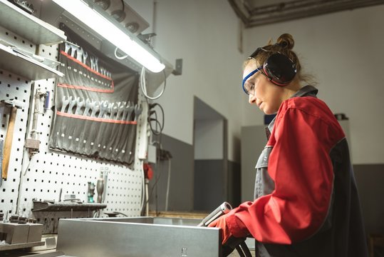 Female worker repairing a machine with tool