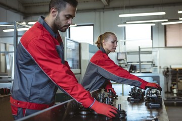 Two workers checking machine parts