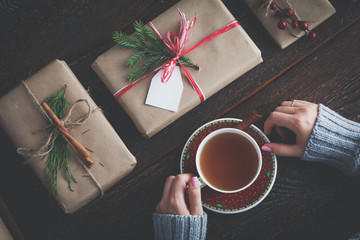 Woman sitting on the desk with christmas gift box. Hands of woman
