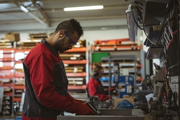 Male worker repairing a machine with tool