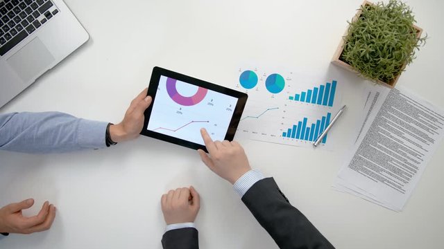 Businessmen analising diagrams in the office. View from the top of men's hands. Close-up shot.