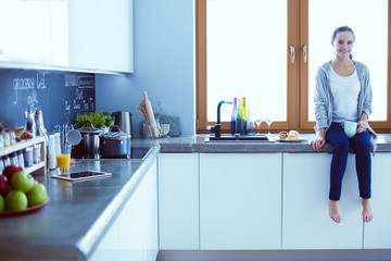 Beautiful young woman using a digital tablet in the kitchen.