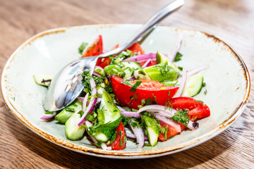 Salad of tomatoes, cucumber, red onion with vegetable oil lies on the plate.