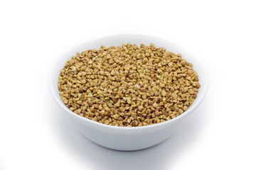 Dry buckwheat in white ceramic bowl isolated on white