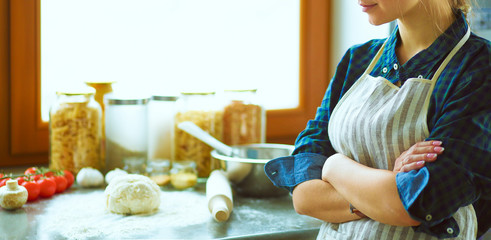 Fototapeta premium Beautiful woman cooking cake in kitchen standing near desk
