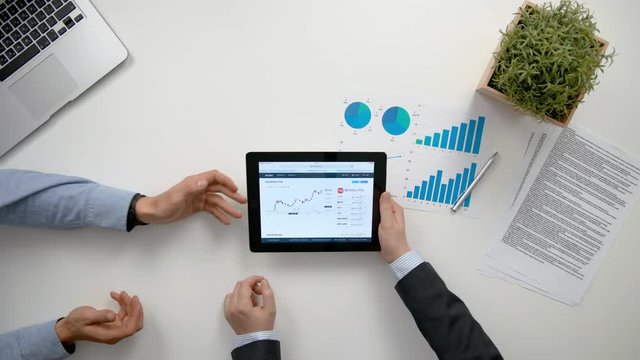 Businessmen analising diagrams in the office. View from the top of men's hands. Close-up shot.