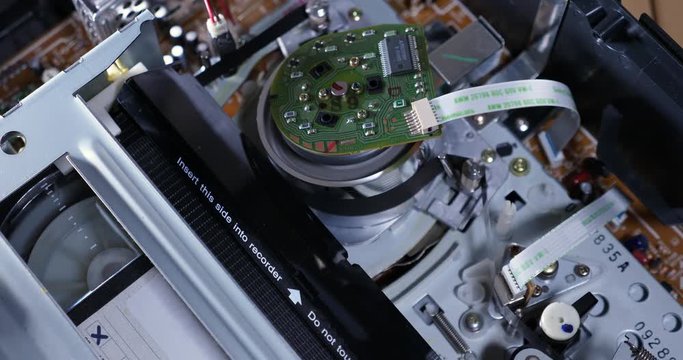 A top down inside view of the electronics of a VCR as a VHS tape is inserted and ejected. Top off view. With audio.	 	