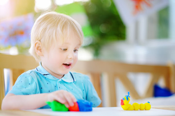 Creative boy playing with colorful modeling clay at kindergarten