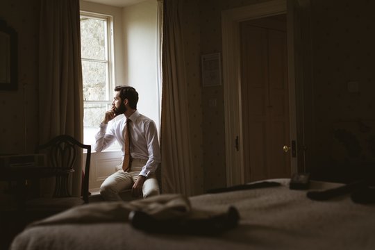 Man looking through window while sitting at home