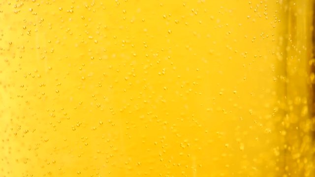Glass full of beer slow moving bubbles. Yellow drink background