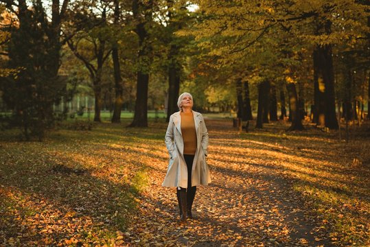 Thoughtful senior woman in jacket looking up in the autumn