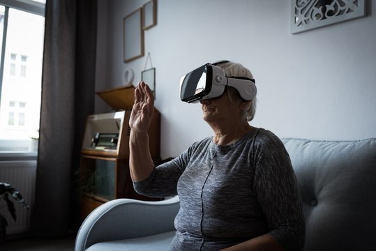 Senior woman using virtual reality headset in living room