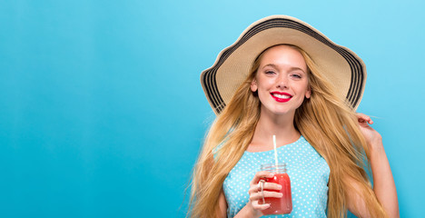 Happy young woman drinking smoothie on a solid background