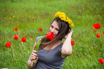 Beautiful fairy young girl in a field among the flowers of tulips. Portrait of a girl on a background of red flowers and a green field. Field of tulips.