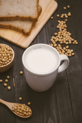 Glass with soy milk and soy bean on wooden background