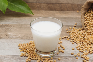 Glass with soy milk and soy bean on wooden background