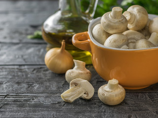 Fresh mushrooms in a yellow bowl on a rustic dark wooden table. Vegetarian food is on the table.