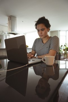 Woman working on laptop while having coffee