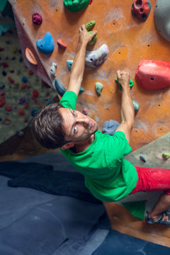 A rock climber is in a bouldering hall.